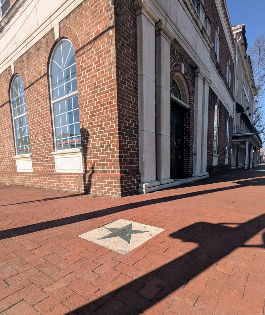 The early afternoon's shadows aside the star with the City National Bank building in the background at Star Corner
