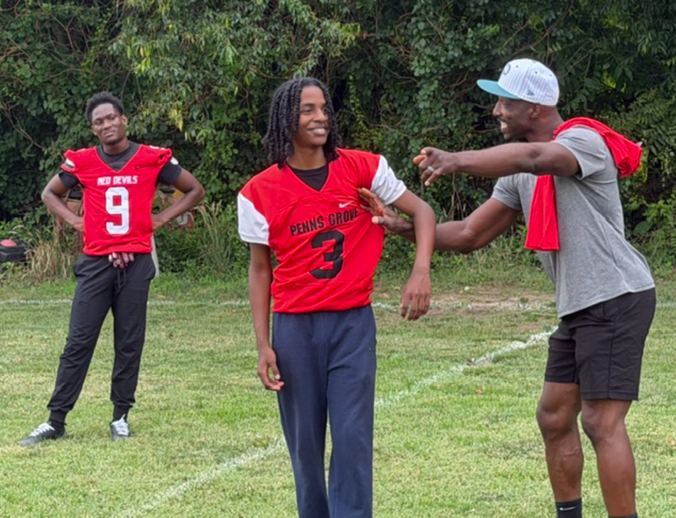 Former NFL receiver Jason Avant points out the nuances of a particular pass pattern to Penns Grove’s Amonte Stone after addressing the team earlier in the day. Isaac Wright (9) listens intently.