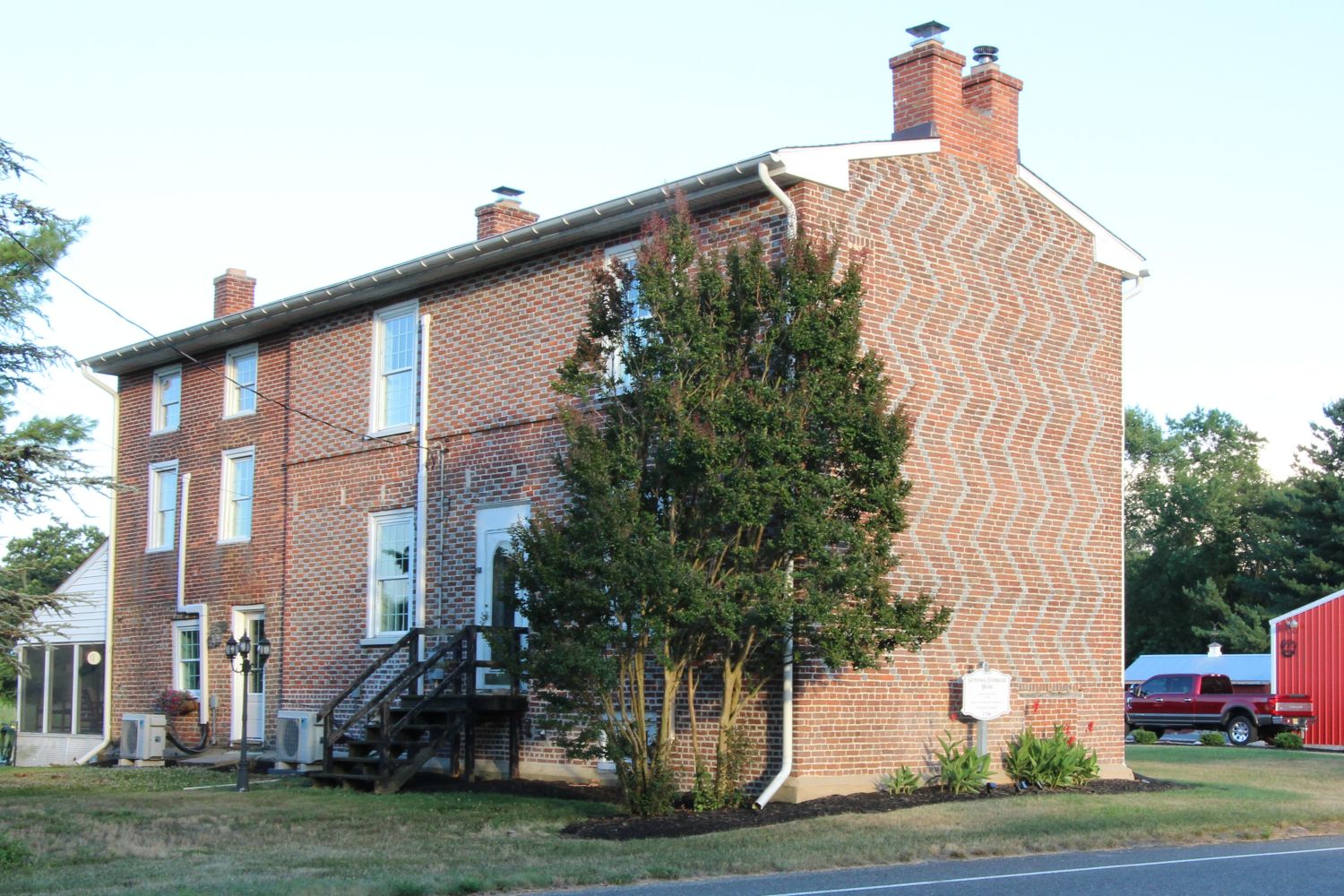 The rear view of the property, revealing the asymmetrical window placement (omitting the center window on the second floor), the checkered stringcourse, and the modern side addition.