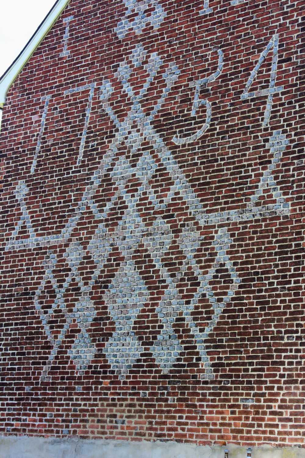 A close-up view of the vitrified brickwork, showing the 17-course-tall "1754" date and central diamond lattice.