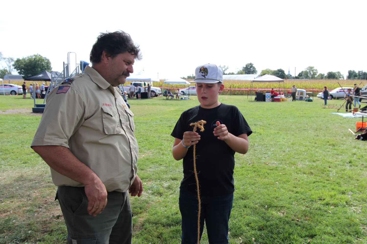 Boy scouts troop leader and member learning how to tie ropes and knots