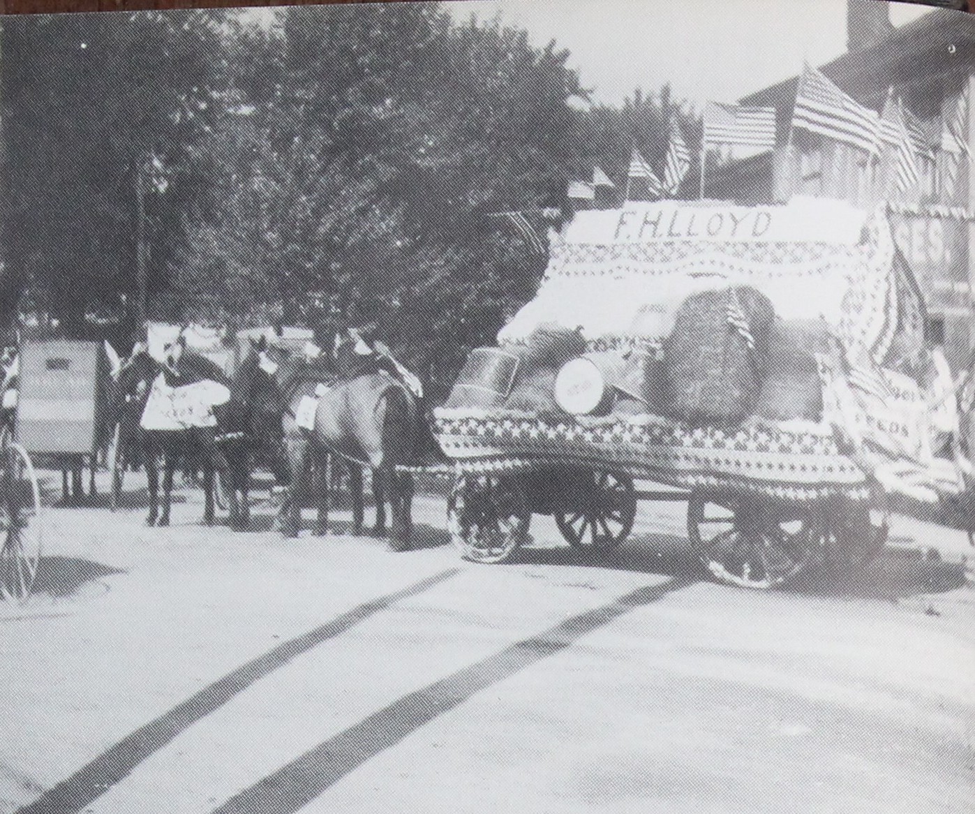 Farmers Float," passing a storefront painted MATTRESSES over the name MEHRLE. The wagon bed is draped in striped bunting, small flags are fixed along the side, and even the wheel spokes have been wrapped. (How Dear to My Heart, p. 30)