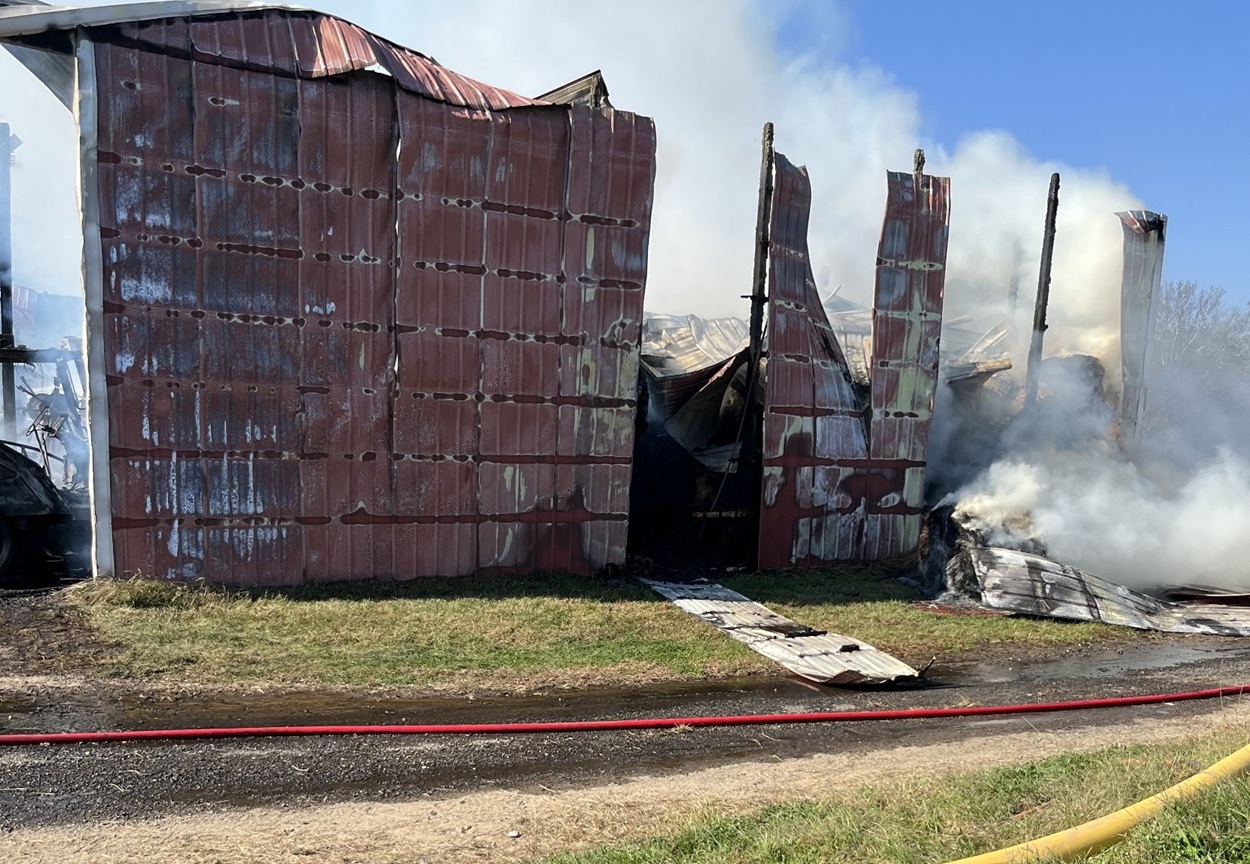 The barn’s red metal walls stand twisted as smoke pours from the hay inside.