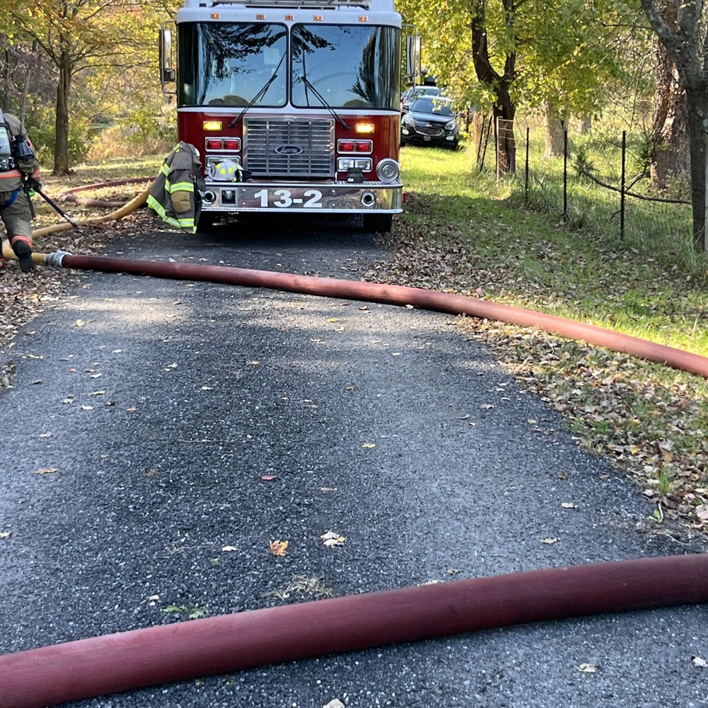 A fire engine staged on the farm lane as hose lines ran toward the barn.